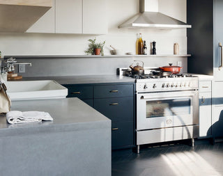 Blue and gray kitchen with stainless accents and gray concrete waterfall countertops.