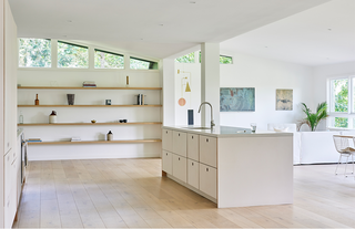 Large white kitchen with open shelving and a sleek island.